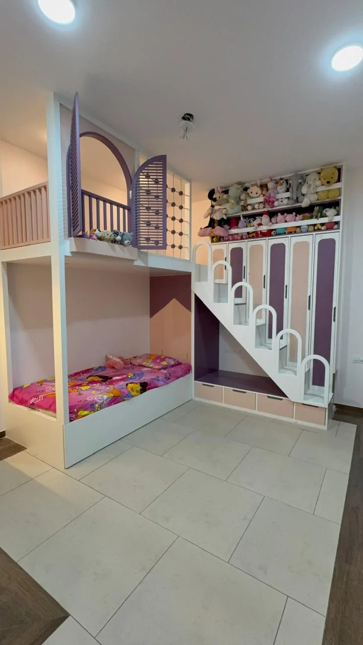 Children’s room with a lower bed, raised loft, storage stairs and pastel built-in wardrobes