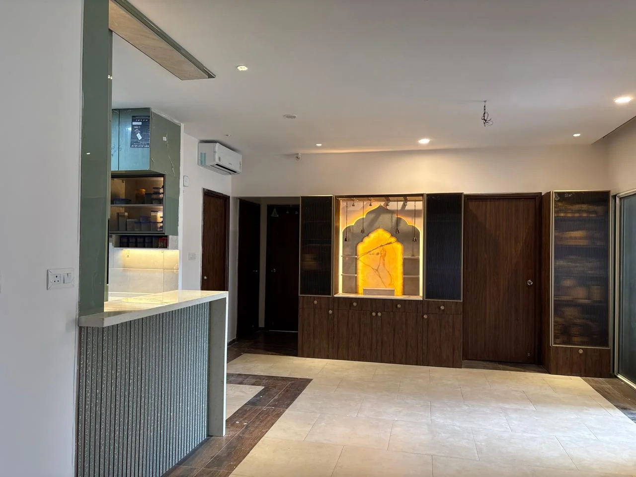 Completed pooja wall with warm backlighting, walnut storage and fluted glass cabinets