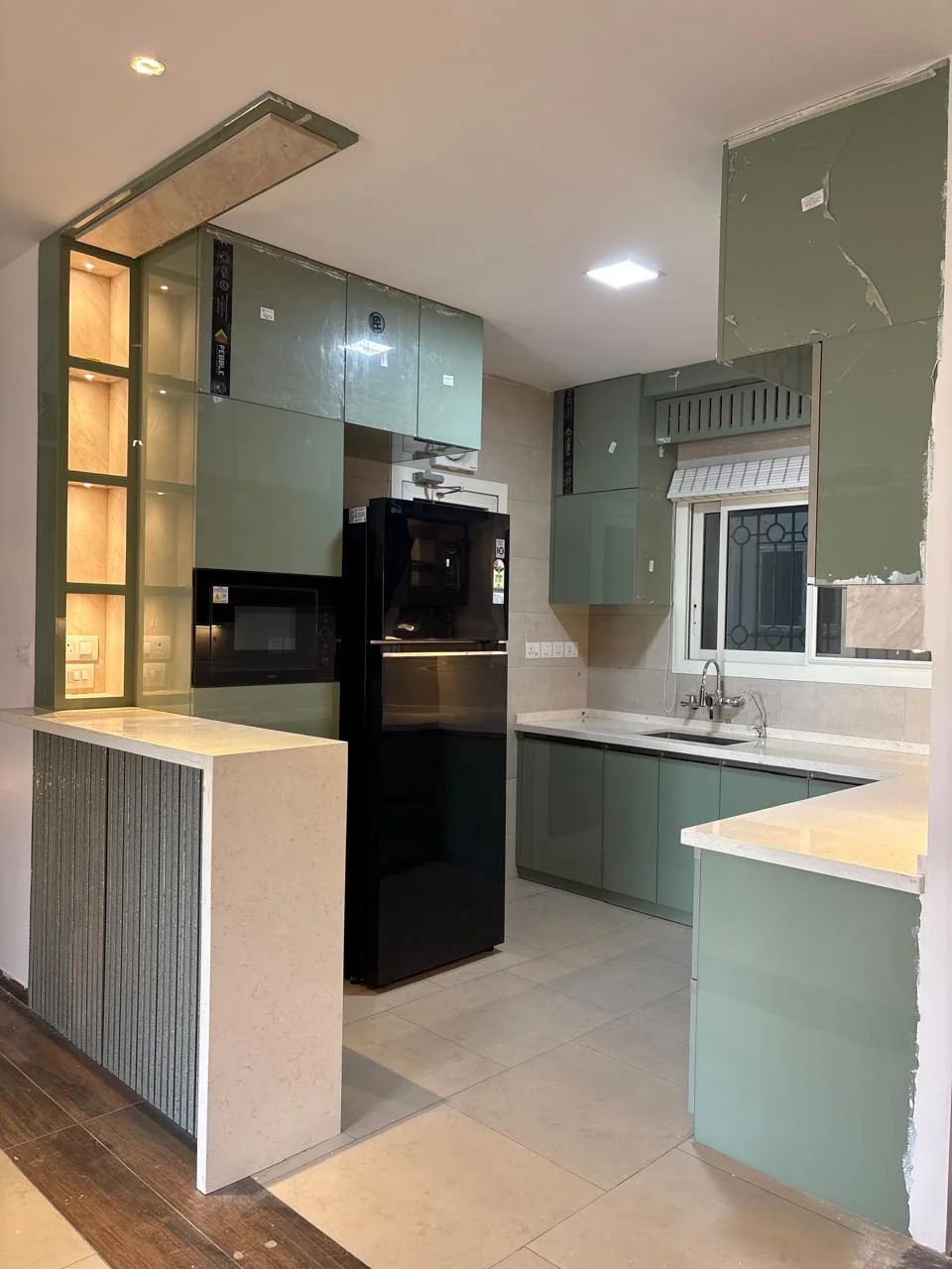 Real modular kitchen in sage green with peninsula, tall storage and built-in appliances